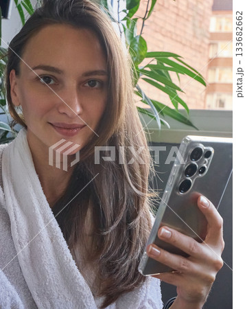Happy Woman Enjoying Morning Relaxation with Smartphone Happy Woman Enjoying Morning Relaxation with Smartphone 133682662