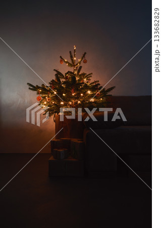 Small christmas tree with natural decorations and gift boxes with warm evening light Small christmas tree with natural decorations and gift boxes with warm evening light 133682829
