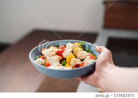 amn hand hold salad with red and yellow cherry tomatoes , mozzarella and spinach in blue bowl amn hand hold salad with red and yellow cherry tomatoes , mozzarella and spinach in blue bowl 133682855