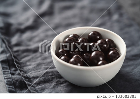 Chocolate drage with hazelnuts nuts in white bowl on linen background Chocolate drage with hazelnuts nuts in white bowl on linen background 133682883