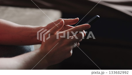 Closeup young man in black t-shirt typing messages on smartphone working from home side view 133682992