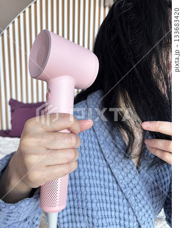 Adult woman drying hair with a pink hair dryer at home, hair care and beauty routine, daily styling process, self care and grooming concept, home interior lifestyle, healthy hair maintenance and moder Adult woman drying hair with a pink hair dryer at home, hair care and beauty routine, daily styling process, self care and grooming concept, home interior lifestyle, healthy hair maintenance and moder 133683420