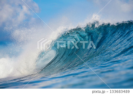 Majestic ocean swell with shimmering sunlight and foamy crest 133683489