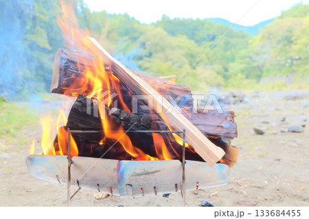 焚き火台で燃え上がる薪と炎のアウトドアシーン 焚き火台で燃え上がる薪と炎のアウトドアシーン 133684455