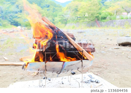 焚き火台で燃え上がる薪と炎のアウトドアシーン 133684456