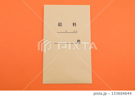 鮮やかなオレンジ色背景に置かれた給料袋 133684644