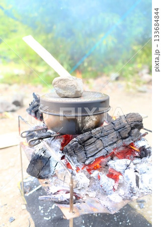 メスティン炊飯と焚き火調理が並ぶアウトドアクッキングの風景 133684844