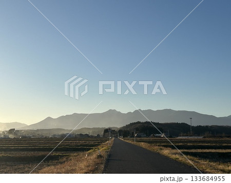 静かな農村に伸びる一本道と夕景の山並み 静かな農村に伸びる一本道と夕景の山並み 133684955