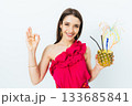 Woman in a pink dress is holding a pineapple and smiling 133685841