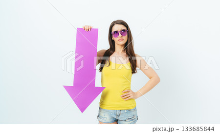 Woman in a yellow shirt is holding a pink sign that says "down" Woman in a yellow shirt is holding a pink sign that says "down" 133685844