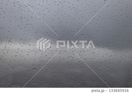 Wet Window Surface with Rain Drops and Blurred Gloomy Background 133685916
