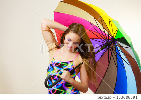 Happy woman posing in swimsuit and colorful umbrella 133686391
