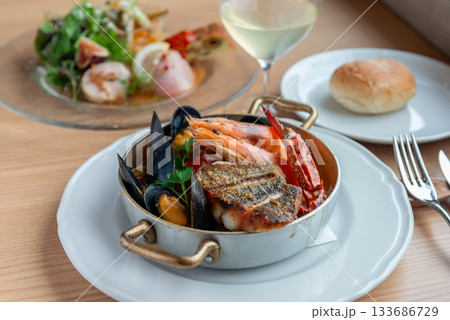 ブイヤベースと前菜、白ワインが並ぶレストランの食卓風景 ブイヤベースと前菜、白ワインが並ぶレストランの食卓風景 133686729