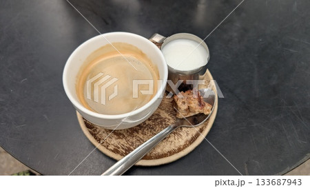 Hot coffee with milk and a small cake on the spoon in Antwerp 133687943