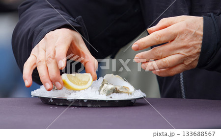 Hands Preparing Fresh Oysters on Ice 133688567