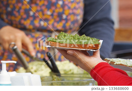 Customer holding basil pesto toast at Prague farmers market Customer holding basil pesto toast at Prague farmers market 133688600