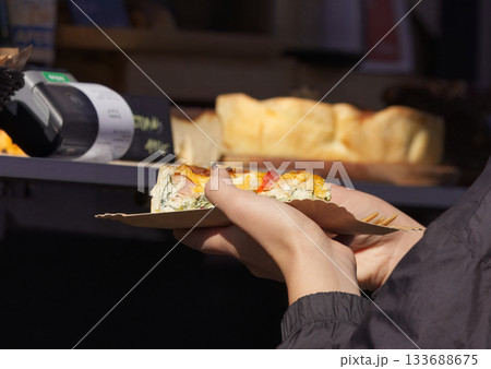 Person holding a slice of savory pie at a street food festival 133688675