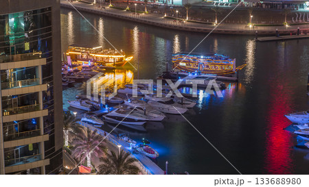 Luxury yachts parked on the pier in Dubai Marina bay with city aerial view night timelapse 133688980