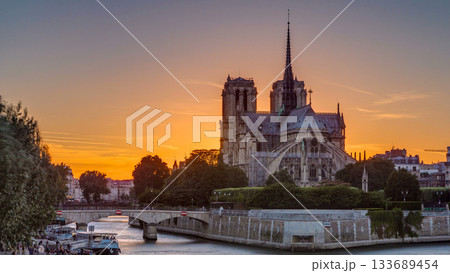 Rear view of Notre Dame De Paris cathedral at sunset with sun in the frame timelapse. 133689454