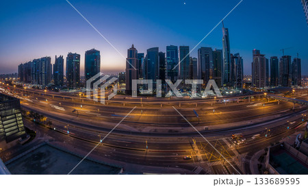 Aerial view of Jumeirah lakes towers skyscrapers night to day timelapse with traffic on sheikh zayed road. Aerial view of Jumeirah lakes towers skyscrapers night to day timelapse with traffic on sheikh zayed road. 133689595