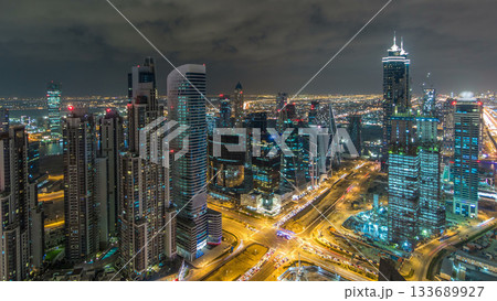 Dubai business bay towers illuminated at night timelapse. Rooftop view of some skyscrapers and new towers under construction. 133689927