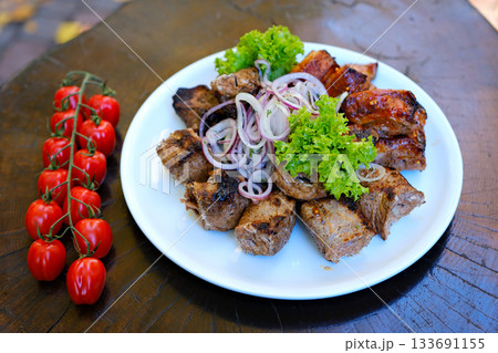 Grilled meat tomatoes Juicy barbecue pork ribs and dry chicken wings with glaze, beer snacks lie on a wooden tray. Grilled meat tomatoes Juicy barbecue pork ribs and dry chicken wings with glaze, beer snacks lie on a wooden tray. 133691155