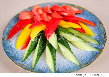 Colorful sliced vegetables of courgette and tomato on the plate on the white background 133691167