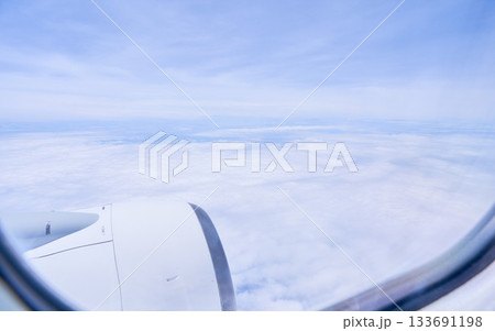 飛行機の窓日中の上空の空と雲の眺め 133691198