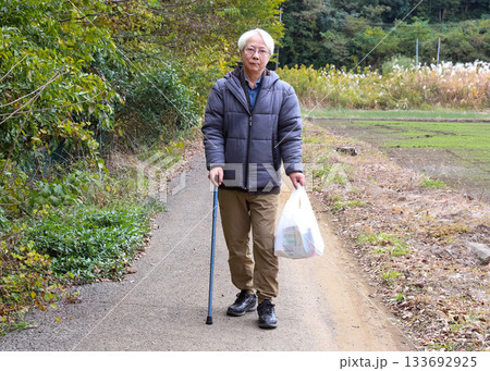 杖をつきながら買い物をするシニア 133692925