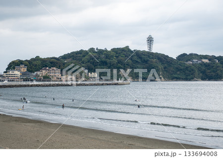 People surfing on beach near forested island with observation tower in cloudy weather People surfing on beach near forested island with observation tower in cloudy weather 133694008