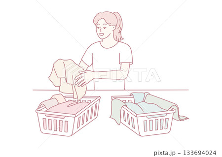 serene woman methodically arranges charitable clothing into baskets during peaceful afternoon 133694024