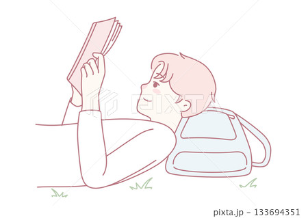 Happy guy lying on ground reading book Happy guy lying on ground reading book 133694351