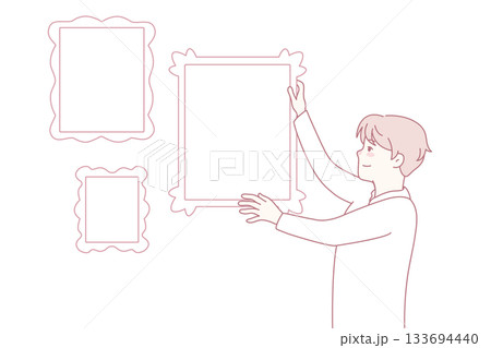 Man hanging frames on wall 133694440
