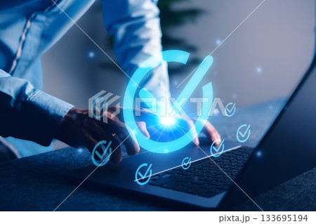 Digital approval concept with glowing checkmark icon on laptop screen, representing task completion, project validation, and goal achievement. 133695194