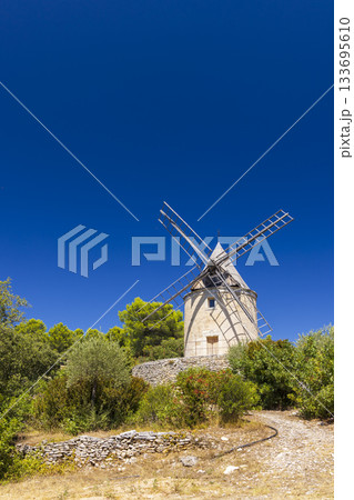 Stone windmill standing in Provence against blue sky Stone windmill standing in Provence against blue sky 133695610
