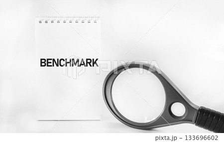The benchmark business concept. The word BENCHMARK written on a white piece of paper next The benchmark business concept. The word BENCHMARK written on a white piece of paper next 133696602