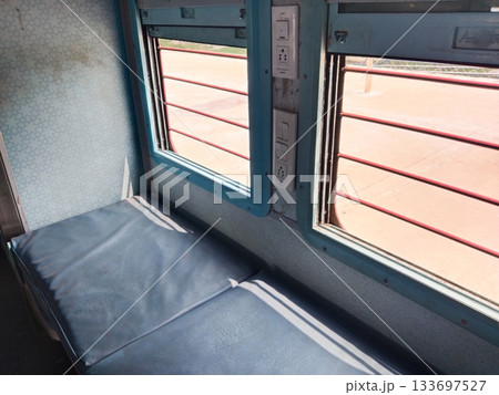 Empty seats, windows and berths inside a second class sleeper compartment in a train run by the Indian Railways. 133697527