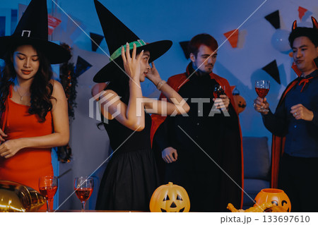 Joyful office Halloween party with coworkers in costumes, celebrating with drinks and laughter, fostering teamwork and festive spirit 133697610