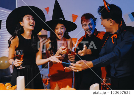 Joyful office Halloween party with coworkers in costumes, celebrating with drinks and laughter, fostering teamwork and festive spirit 133697625
