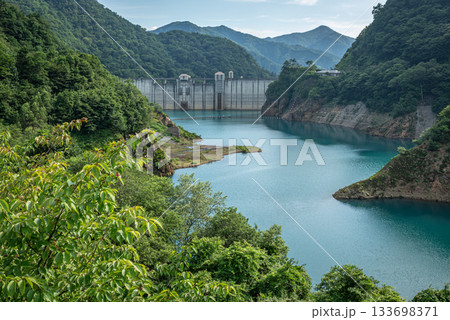 夏の奥四万湖と四万川ダムを望む鮮やかなエメラルドブルーの湖面 133698371