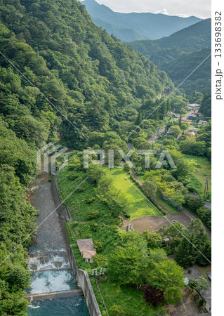 群馬県中之条町・四万川ダムから望む夏の渓谷と集落の風景 133698382