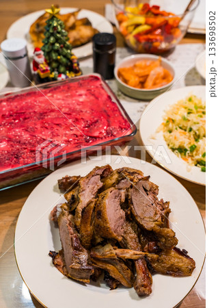 Festive table with roast duck and traditional herring under a fur coat salad Festive table with roast duck and traditional herring under a fur coat salad 133698502