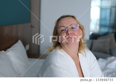 Home, kiss and portrait of woman on bed for relaxing, resting and comfortable in bedroom in morning. Apartment, blanket and person with wink, pout and wake up for health, wellness and weekend 133698733