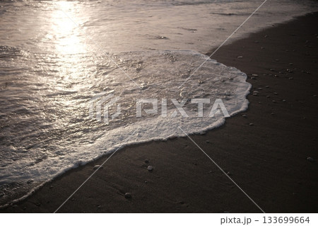 Shoreline at the beach with a setting sun, waves sand and no people Shoreline at the beach with a setting sun, waves sand and no people 133699664