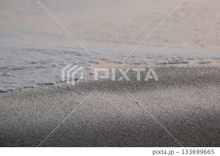 Shoreline at the beach with a setting sun, waves sand and no people Shoreline at the beach with a setting sun, waves sand and no people 133699665