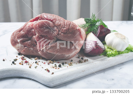 Raw pork knuckle, on a wooden chopping board, with spices, close-up, top view, no people, 133700205
