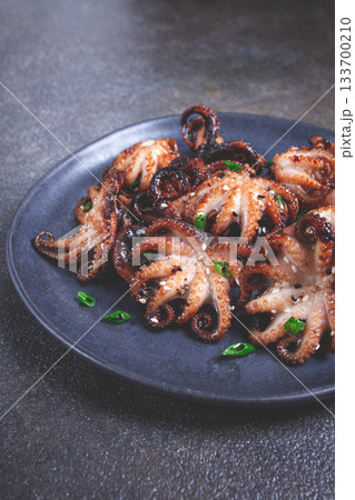 Grilled baby octopus, served with chopsticks, on a black plate, homemade, no people, 133700210