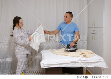 father ironing a shirt And Daughter Ironing Fabric For Sewing With A Steam Iron 133701599