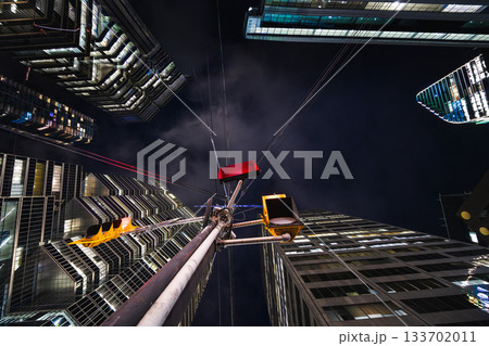A lone traffic signal rises into a canyon of towering glass, its red glow contrasting with the cold geometry of the surrounding skyscrapers. A lone traffic signal rises into a canyon of towering glass, its red glow contrasting with the cold geometry of the surrounding skyscrapers. 133702011