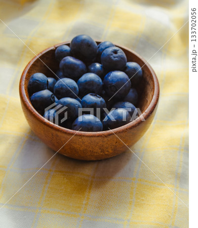 Fresh blueberries in a rustic wooden bowl, set on a colourful tablecloth. Freshly harvested organic fruit .Ideal for healthy diets. Fresh blueberries in a rustic wooden bowl, set on a colourful tablecloth. Freshly harvested organic fruit .Ideal for healthy diets. 133702056